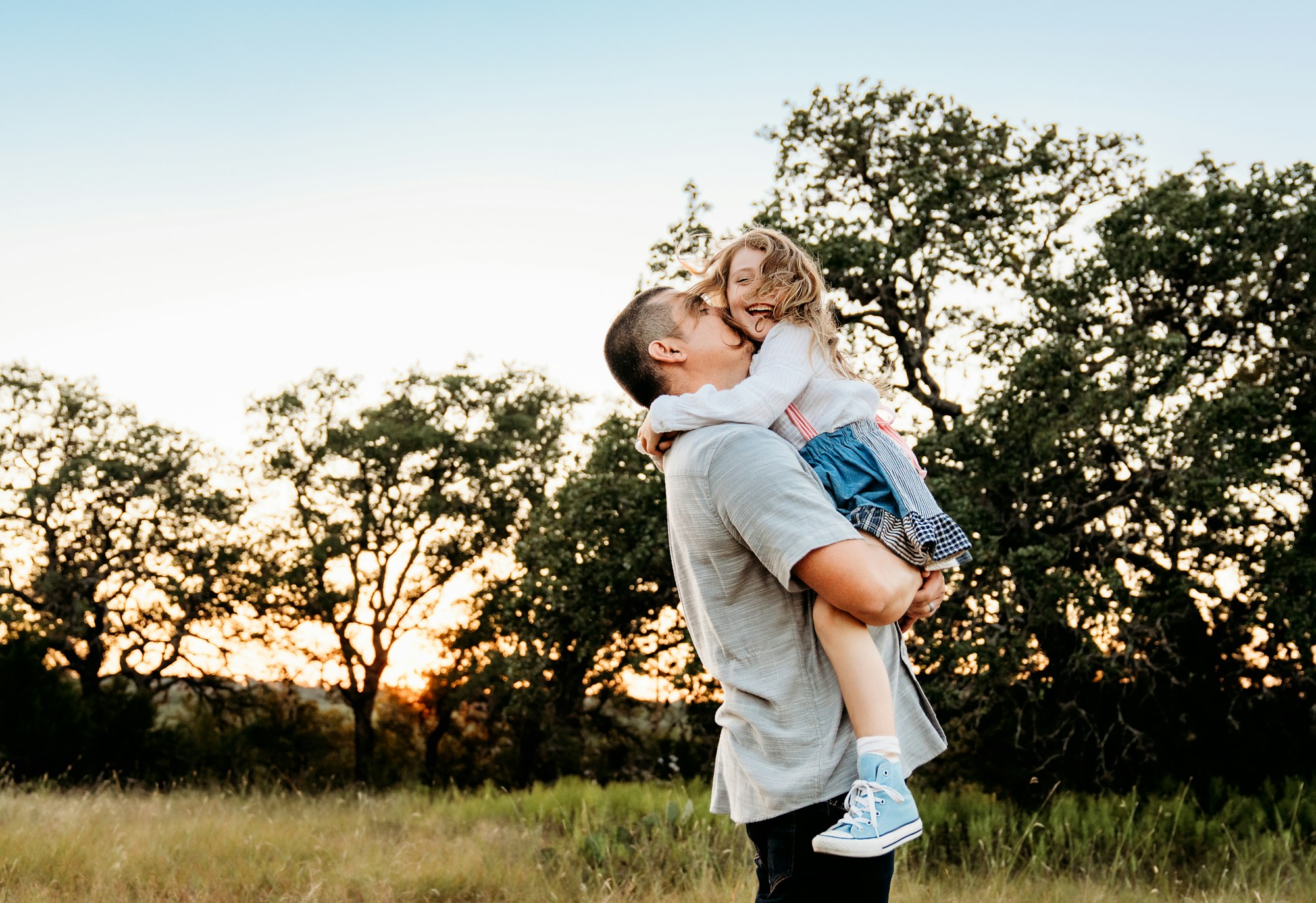 A father holding his young daughter in the evening sunshine